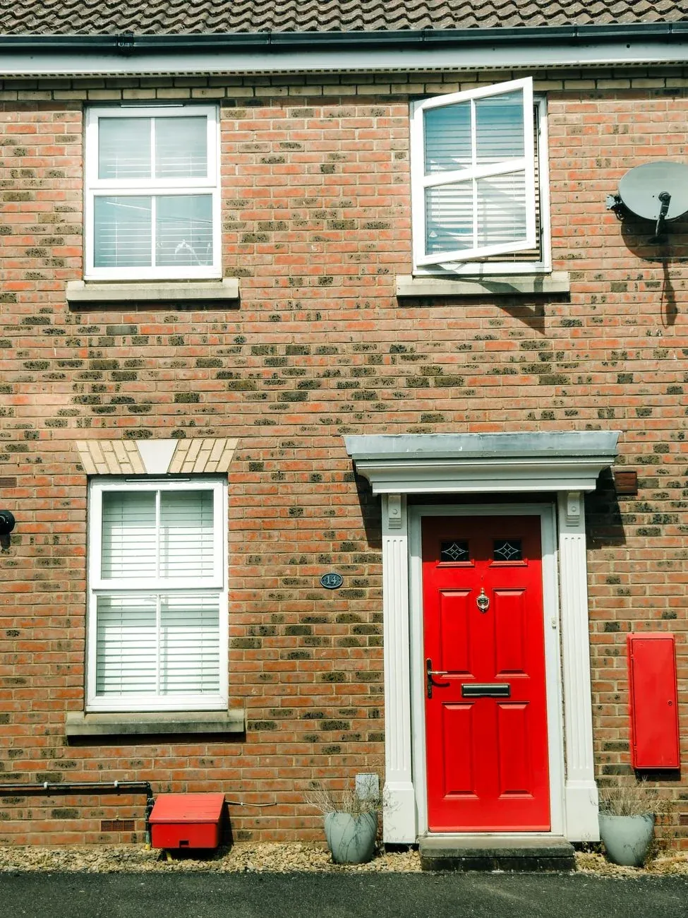 A Georgian brick house with a red front door and white windows
